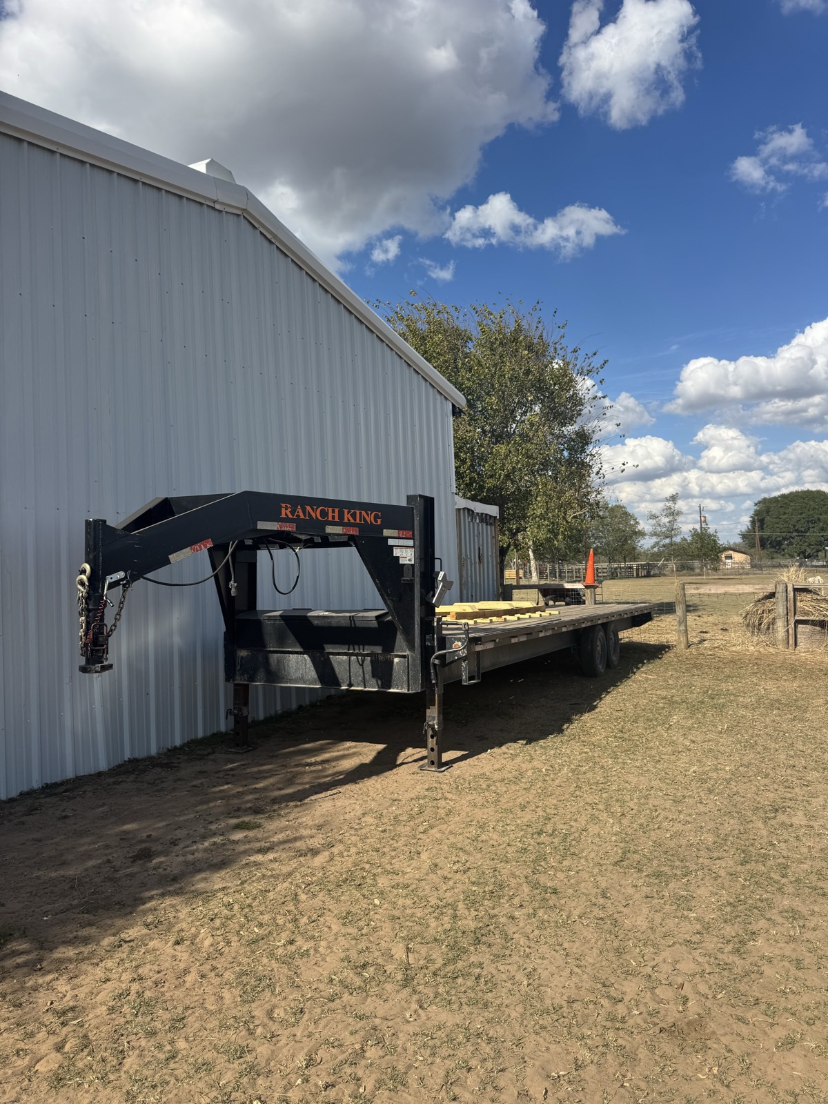 Ranch King gooseneck flatbed trailer parked by a barn